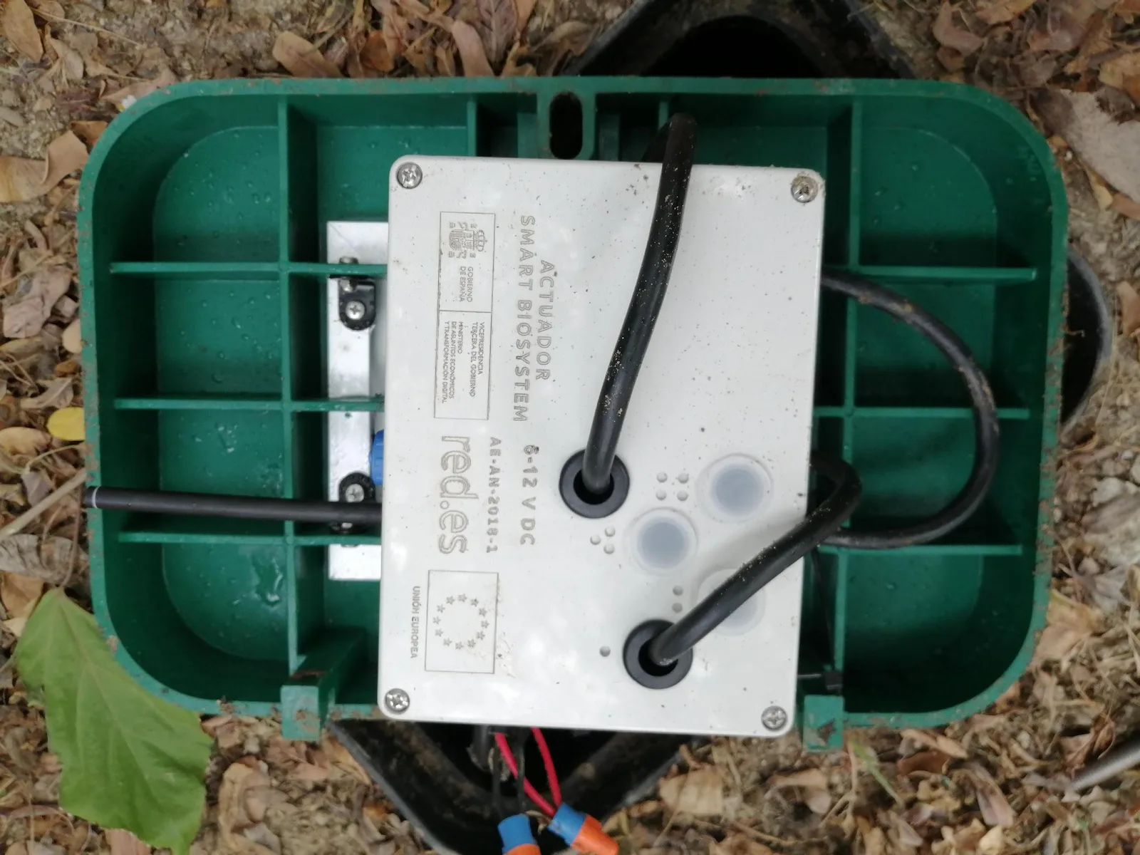 Smart Biosystem actuator unit inside a green valve box, showing red.es, Government of Spain and European Union markings